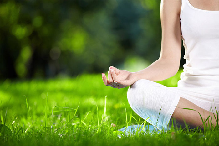 mujer-meditando-sentada-en-el-cesped